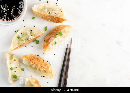 Gyoza fritto o Jiaozi su sfondo marmoreo, gnocchi cinesi con carne e verdure. Spazio di copia vista dall'alto Foto Stock
