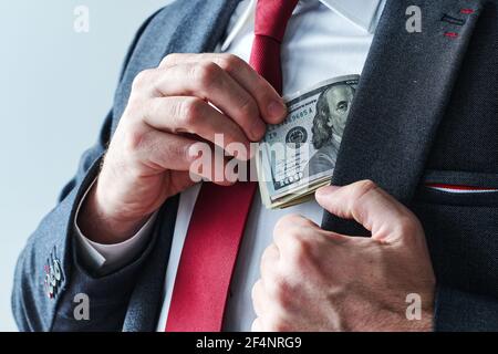 Uomo d'affari che prende i soldi in contanti del dollaro degli Stati Uniti dalla sua tasca del vestito, primo piano di uomo d'affari elegante Foto Stock