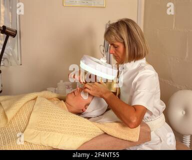 Beautican che fa massaggio facciale su giovane donna, Winkfield, Berkshire, Inghilterra, Regno Unito Foto Stock