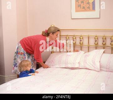 Giovane madre e figlia che fanno il letto, Winkfield, Berkshire, Inghilterra, Regno Unito Foto Stock