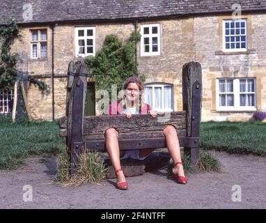 Giovane donna che posa in stock di villaggio, Market Square, Stow-on-the-Wold, Gloucestershire, Inghilterra, Regno Unito Foto Stock