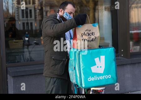 L'uomo Delvieroo che indossa la maschera, mette il cibo da asporto di Nando in una borsa montata sulla sua moto, Londra, Inghilterra Foto Stock
