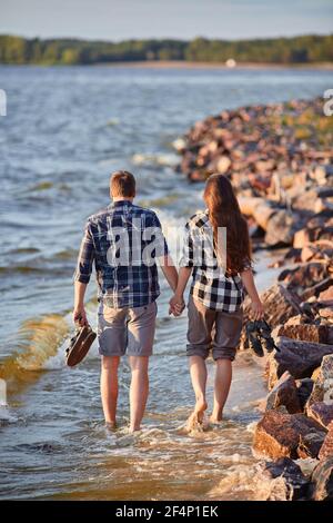 Paio di camminare sulla spiaggia al tramonto Foto Stock