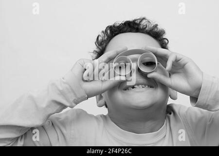 ragazzo guardando attraverso il rotolo di carta binocolo su sfondo bianco foto stock Foto Stock