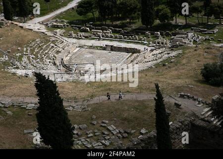 Atene, Grecia. 22 marzo 2021. La gente visita l'antico Teatro di Dioniso vicino all'Acropoli di Atene, Grecia, il 22 marzo 2021. Lunedì, i siti archeologici all'aperto, tra cui la collina dell'Acropoli di Atene, hanno riaperto per la prima volta dall'inizio della chiusura. Solo un piccolo gruppo di visitatori è autorizzato a visitare e l'uso di maschere facciali di protezione è obbligatorio. Credit: Lefteris Partsalis/Xinhua/Alamy Live News Foto Stock