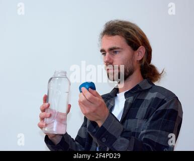 Spagnolo giovane maschio bearded che tiene una bottiglia d'acqua sopra lo sfondo bianco Foto Stock
