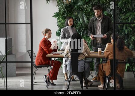 Ritratto grafico a lunghezza intera di diversi gruppi di uomini d'affari che si incontrano al tavolo in un moderno ufficio interno, spazio di copia Foto Stock