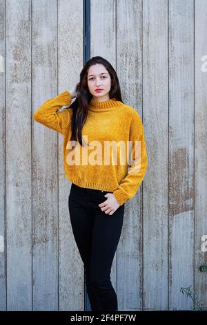 Foto verticale di un Ritratto di una giovane bruna con labbra dipinte e in un pullover giallo Foto Stock