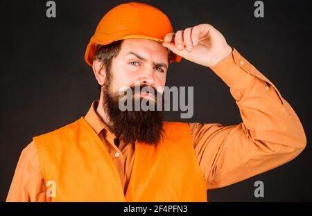 Ingegnere professionale del settore pesante. Lavoratore di costruzione in elmetto. Uomo bearded in uniforme di sicurezza e casco. Costruttore maschile. Foto Stock