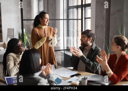 Ritratto di una donna d'affari mediorientale di successo che applaude durante l'incontro con diverse persone gruppo di persone in ufficio Foto Stock