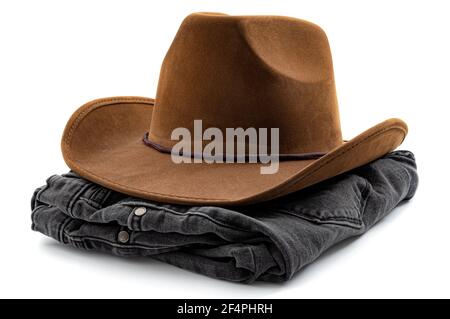 Abbigliamento da cowboy americano, design occidentale e idea concettuale di moda country con paio ripiegato di jeans denim neri e cappello da cowboy marrone isolato su bianco Foto Stock