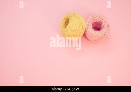 Vista dall'alto di un filato giallo e rosa su a. sfondo rosa con spazio per il testo Foto Stock