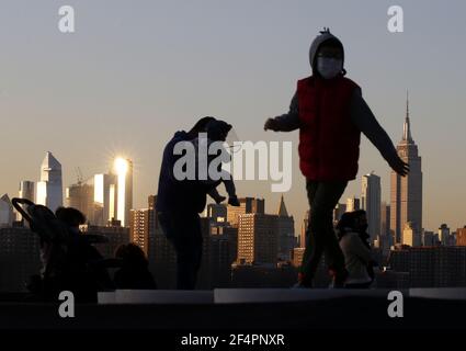 Brooklyn, Stati Uniti. 22 marzo 2021. Un bambino indossa uno scudo protettivo del coronavirus mentre gioca su un'installazione d'arte di piattaforme incandescenti intitolate "Reflect" in Domino Park a New York City lunedì 22 marzo 2021. Foto di John Angelillo/UPI Credit: UPI/Alamy Live News Foto Stock