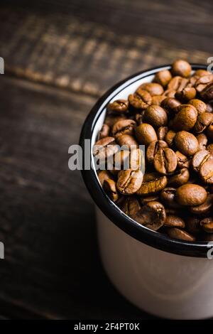 Tazza di metallo piena di chicchi di caffè. Messa a fuoco selettiva. Profondità di campo poco profonda. Foto Stock