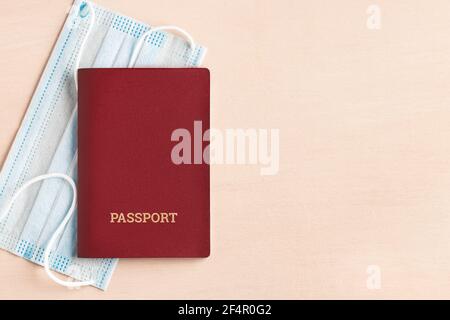 Viaggio sicuro durante il concetto di pandemia di coronavirus. Maschera medica protettiva e passaporto sul tavolo, copyspace, flatlay. Foto Stock