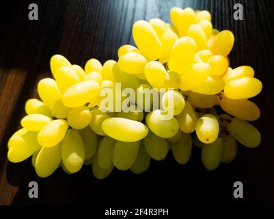 mazzo di uve fresche verdi isolato su sfondo ligneo Foto Stock