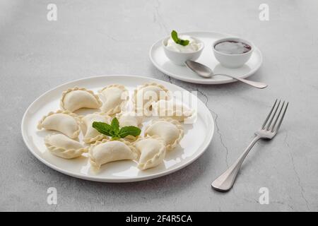 Surgelati semilavorati di vareniki ripieni di ciliegia su sfondo grigio Foto Stock