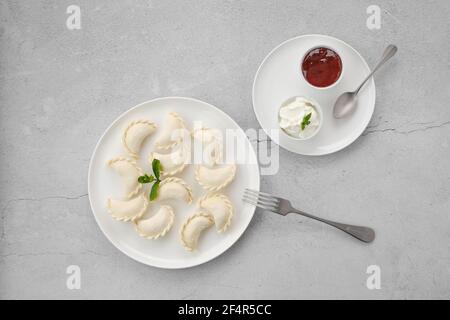 Surgelati semilavorati di vareniki ripieni di ciliegia su sfondo grigio Foto Stock