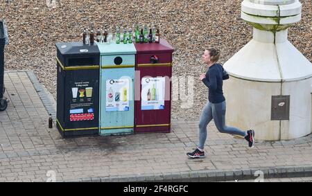 Brighton UK 23 marzo 2021 - UN corridore passa con bottiglie di bevande vuote sul lungomare di Brighton il primo anniversario del coronavirus COVID-19 blocco nel Regno Unito, in quanto il paese segnerà una giornata nazionale di riflessione con un minuto di silenzio a mezzogiorno e candele accese sui gradini della porta Stasera : Credit Simon Dack / Alamy Live News Foto Stock