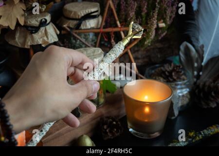 La mano della donna sta tenendo la bacchetta magica che esegue un rituale pagano. Foto Stock