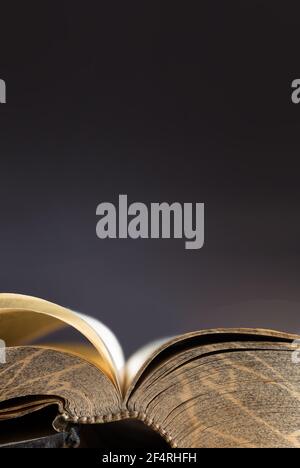 Apri il vecchio libro o la bibbia con un modello sul bordo delle pagine con un'atmosfera simile all'oro e rilegatura cucita. Immagine verticale, sfondo nero Foto Stock