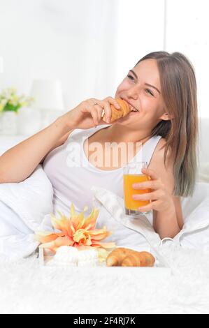Giovane bella donna avente la colazione a letto Foto Stock