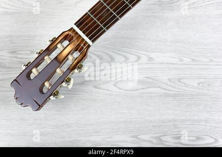 Testa e collo di una chitarra classica su un tavolo di legno bianco, con spazio per la copia Foto Stock