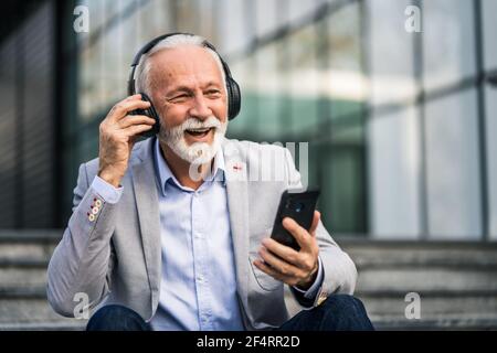 Felice uomo d'affari senior è rilassante dopo il lavoro di fronte alla costruzione dell'azienda. Foto Stock
