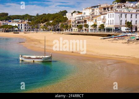 Una piccola barca viene lavata sulla spiaggia di Llafranc in un giorno di primavera quando la spiaggia è vuota. Palafrugell, Catalogna, Spagna Foto Stock