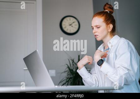 Giovane donna d'affari che soffre di testa rossa che ha dolore al polso durante il lavoro sul computer portatile Foto Stock