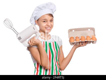 Teen girl in cappello chef in grembiule con frusta d'uovo, isolato su sfondo bianco. Foto Stock