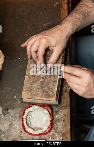 gioielleria orafa saldando un anello argentato sul banco da lavoro con una saldatura. Foto Stock