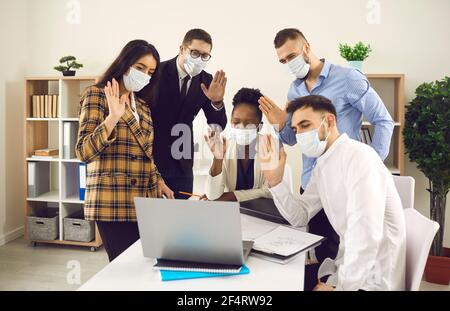 Team aziendale diversificato in maschere protettive con videoconferenza su computer portatile Foto Stock