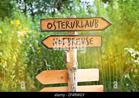 Cartello in legno con la scritta tedesca Osterurlaub (vacanze di Pasqua) E Notbremse (freno di emergenza) Foto Stock