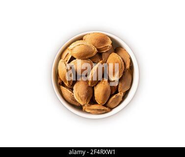 Studio di albicocche su sfondo bianco. Mucchio di buca di albicocca in nutshell isolato su bianco. Noci in un recipiente con spazio per la copia del testo. Mandorle c Foto Stock