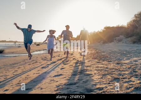 giovani amici che giocano e si divertono mentre corrono e saltano in spiaggia in vacanza. attività estiva. concetto di amicizia, divertimento e unità Foto Stock