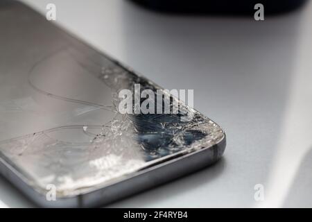 Primo piano di uno schermo di vetro rotto su uno smartphone, isolato su uno sfondo bianco Foto Stock