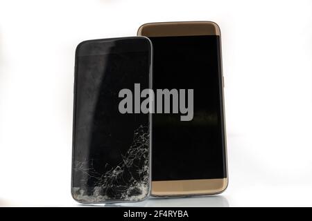 Uno schermo dello smartphone rotto e incrinato accanto a un funzionante e smartphone appena riparato Foto Stock