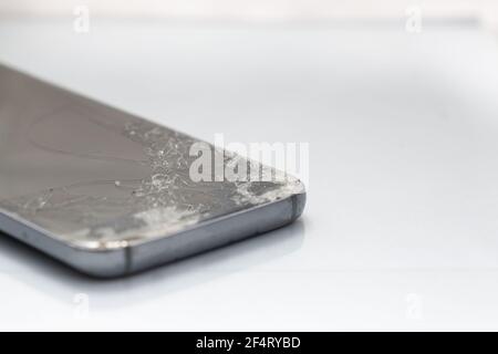 Primo piano di uno schermo di vetro rotto su uno smartphone, isolato su uno sfondo bianco Foto Stock