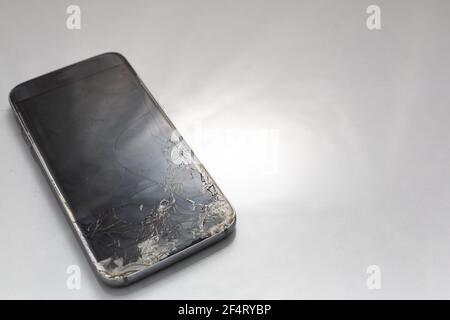 Primo piano di uno schermo di vetro rotto su uno smartphone, isolato su uno sfondo bianco Foto Stock