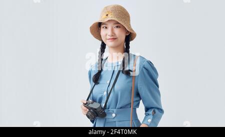 Attraente donna asiatica energica felicemente tenendo cemara isolato su grigio sfondo Foto Stock