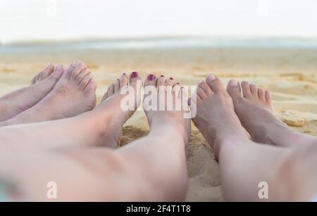 gruppo di amici piedi riposarsi e rilassarsi sulla spiaggia con l'oceano in background. vacanza e amicizia concetto. Foto Stock