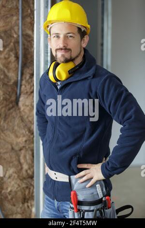 ritratto di un uomo sorridente che indossa un cappello giallo nel cantiere Foto Stock