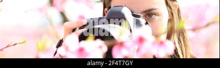 Banner orizzontale di una donna che fotografa fiori con una fotocamera dslr e obiettivo macro in un campo Foto Stock