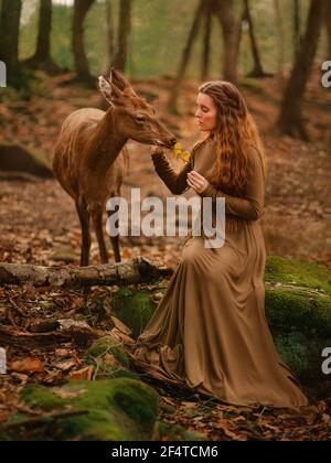 Ragazza di testa rossa con cervo in un vestito lungo Foto Stock