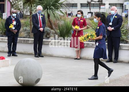 Un membro del personale porta fiori da collocare ai piedi della statua dell'infermiera della Guerra di Crimea Mary Seacole durante una cerimonia per osservare un minuto di silenzio al St Thomas' Hospital, nel centro di Londra, Come parte della Giornata Nazionale di riflessione, nell'anniversario del primo blocco nazionale per prevenire la diffusione del coronavirus. Data immagine: Martedì 23 marzo 2021. Foto Stock