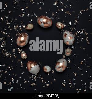 Uova dorate e confetti luminosi su sfondo nero. Foto Stock