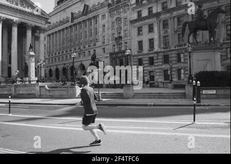 Un uomo che fa jogging per le strade della città Londra a pranzo 1 anno dopo dal Covid 19 blocco Foto Stock