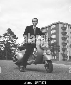 Vespa. Un marchio italiano di scooter prodotto da Piaggio. In data 23 aprile 1946 Piaggio & C. S.p.A. ha depositato un brevetto per "un ciclo motore con un razionale complesso di organi ed elementi con carrozzeria in combinazione con i parafanghi e il cofano coprendo tutte le parti meccaniche". Poco dopo, la Vespa fece la sua prima apparizione pubblica. È Henry Hasso, figlio dell'attrice Signe Hasso nel luglio 1952. Foto Stock