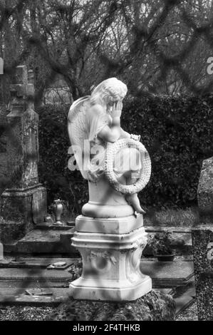 Vecchio cimitero con angelo lutto sulla tomba che tiene la corona con parola ricordo (memoria in francese) visto attraverso recinto. Francia. Dolore, perdita, tristezza con Foto Stock